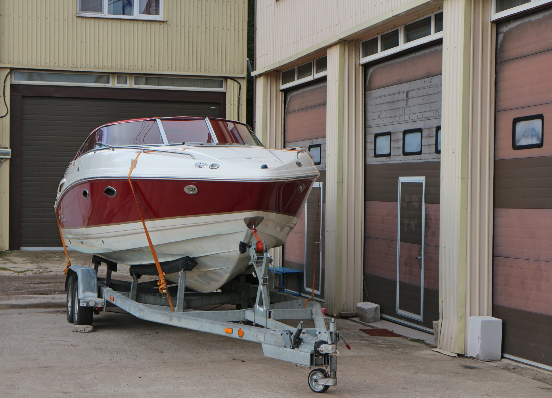 Red boat on trailer near garage