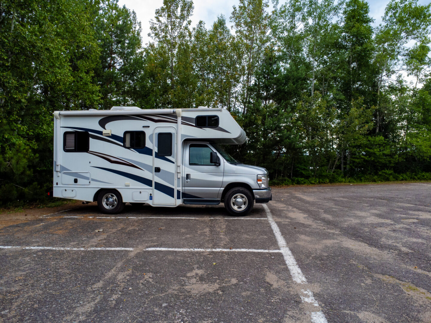 Side view of motorhome in parking lot of nature park during summer day